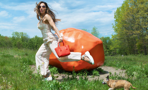 Bianca Jade running with dog at Art Omi Sculpture Park in front of a big orange rock sculpture
